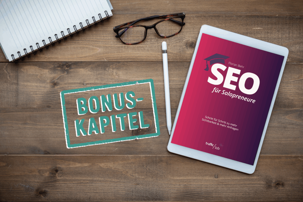 ebook "Seo für Solopreneure" auf Holztisch mit Brille und Stift. Auf dem Tisch ein Stempel "Bonus-Kapitel"